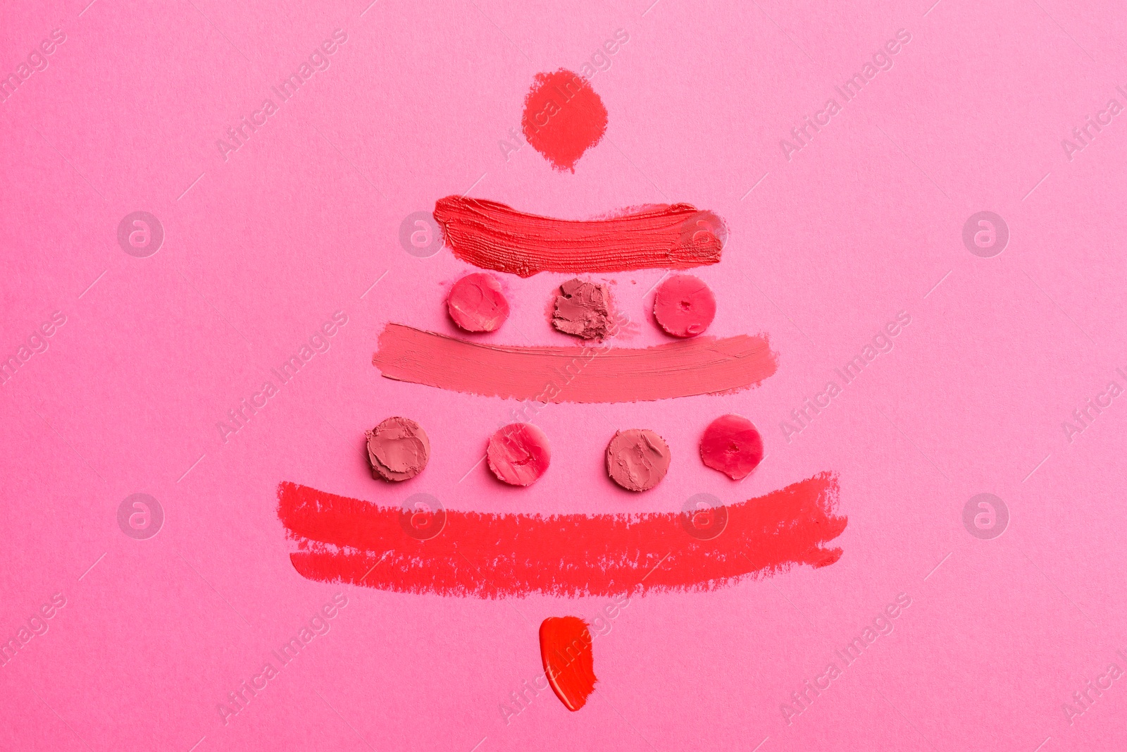 Photo of Christmas tree drawn with lipsticks on pink background, top view