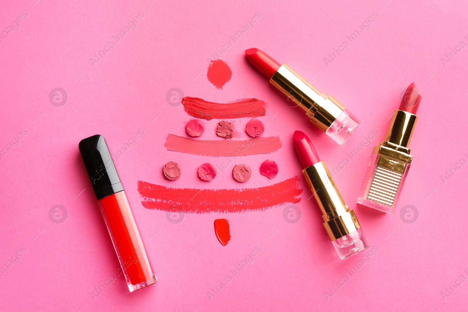 Photo of Christmas tree drawn with lipsticks on pink background, flat lay