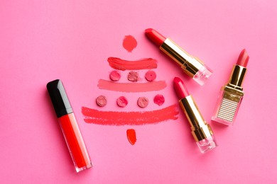 Photo of Christmas tree drawn with lipsticks on pink background, flat lay