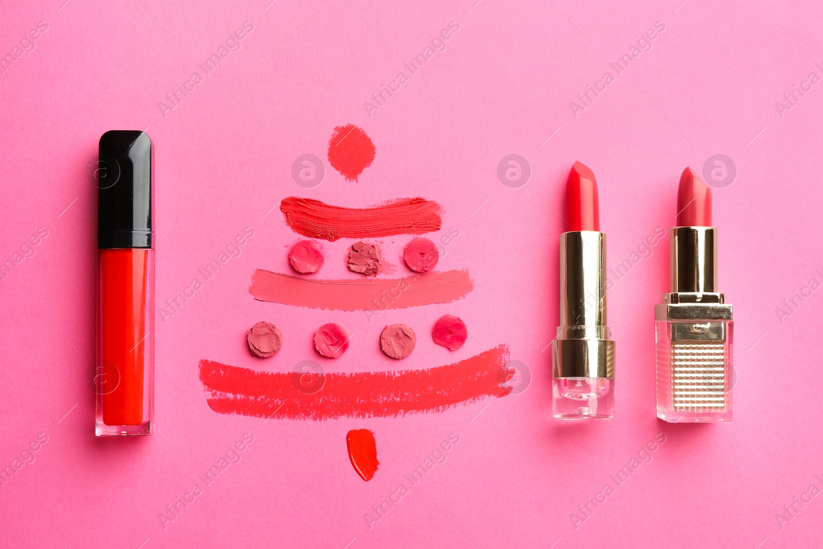 Photo of Christmas tree drawn with lipsticks on pink background, flat lay