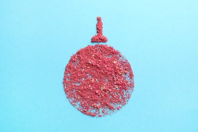 Photo of Christmas ball made with blush on light blue background, top view