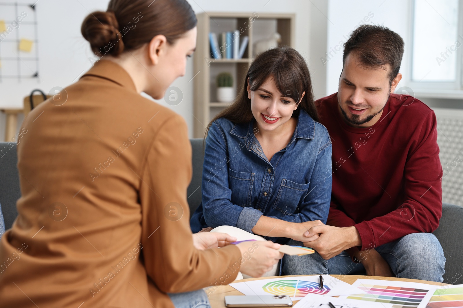 Photo of Designer discussing project with clients at table in office