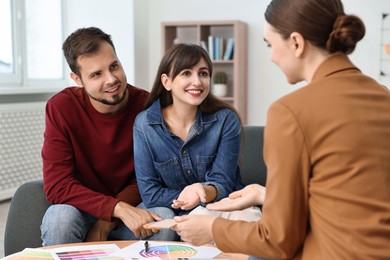 Photo of Designer discussing project with clients at table in office