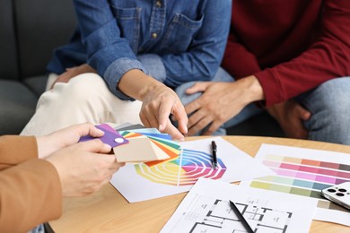 Designer discussing project with clients at table indoors, closeup