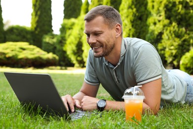 Photo of Man using laptop on green lawn outdoors