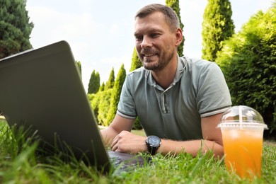 Photo of Man using laptop on green lawn outdoors