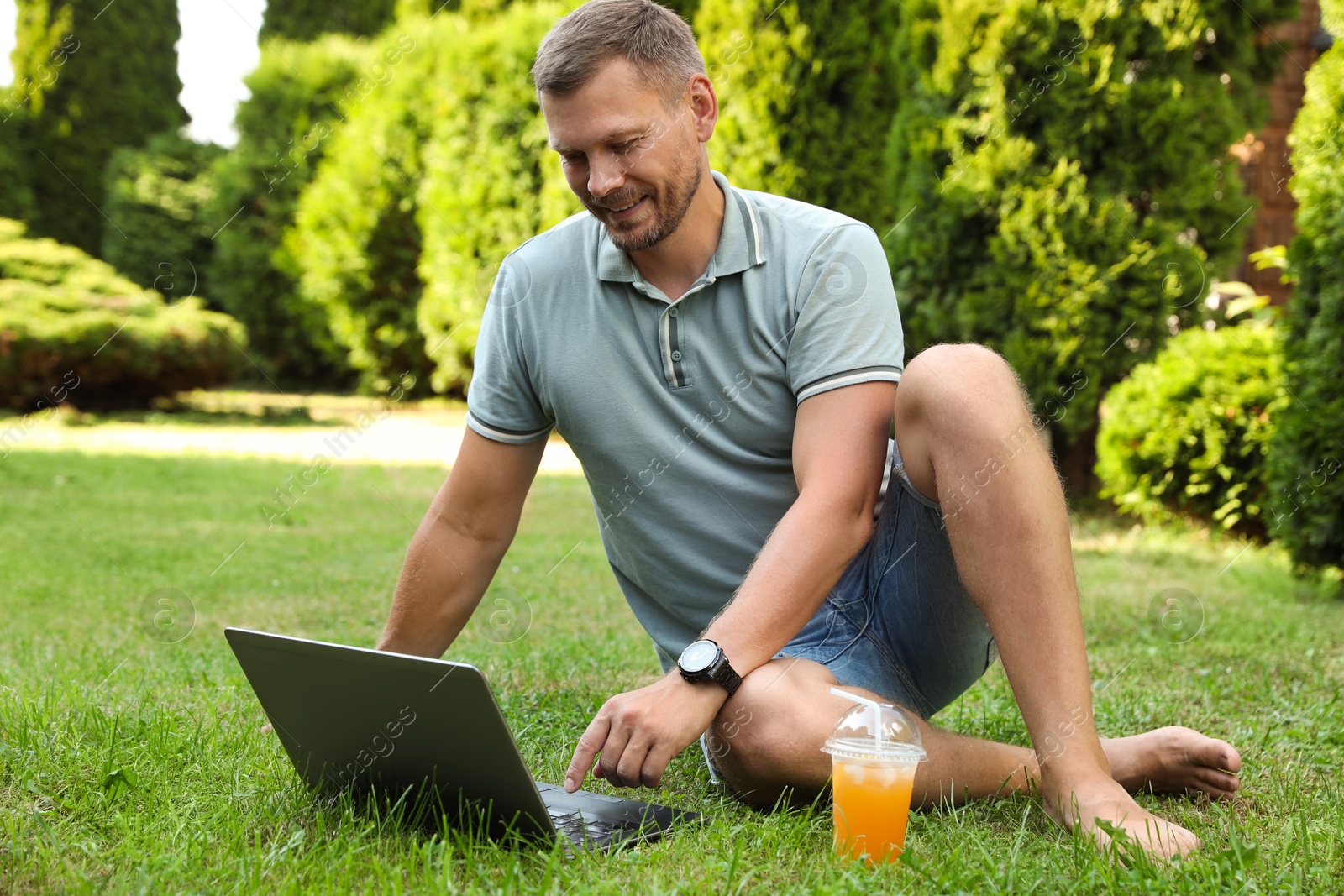 Photo of Man using laptop on green lawn outdoors