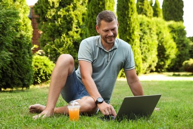 Man using laptop on green lawn outdoors