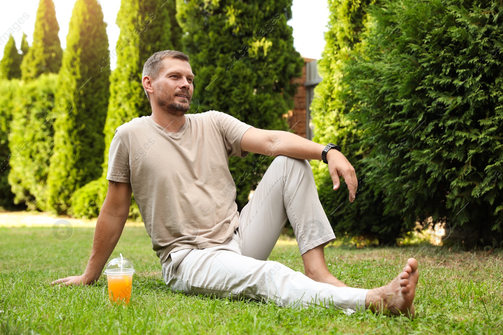 Photo of Handsome man sitting on green lawn outdoors