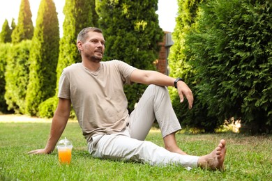 Handsome man sitting on green lawn outdoors