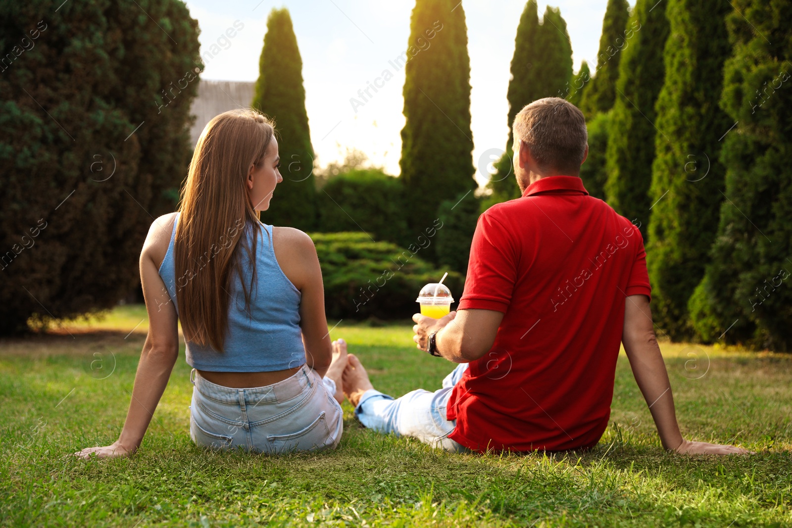 Photo of Couple spending time together on green lawn in park, back view