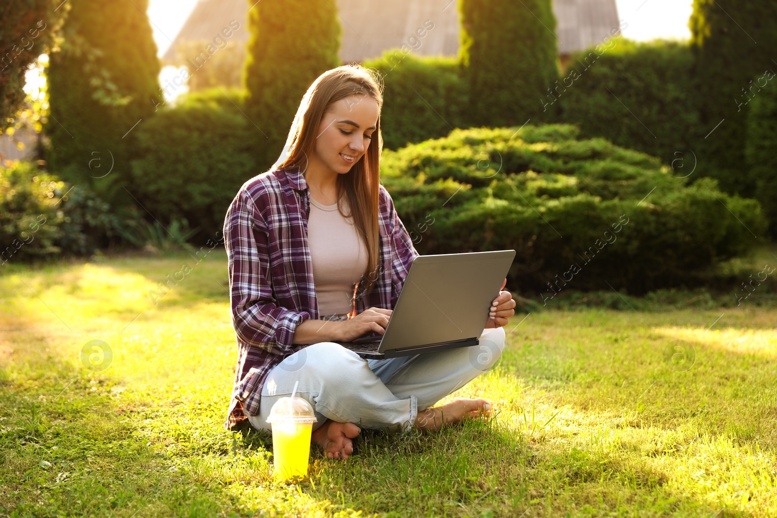 Photo of Woman using laptop on green lawn in park