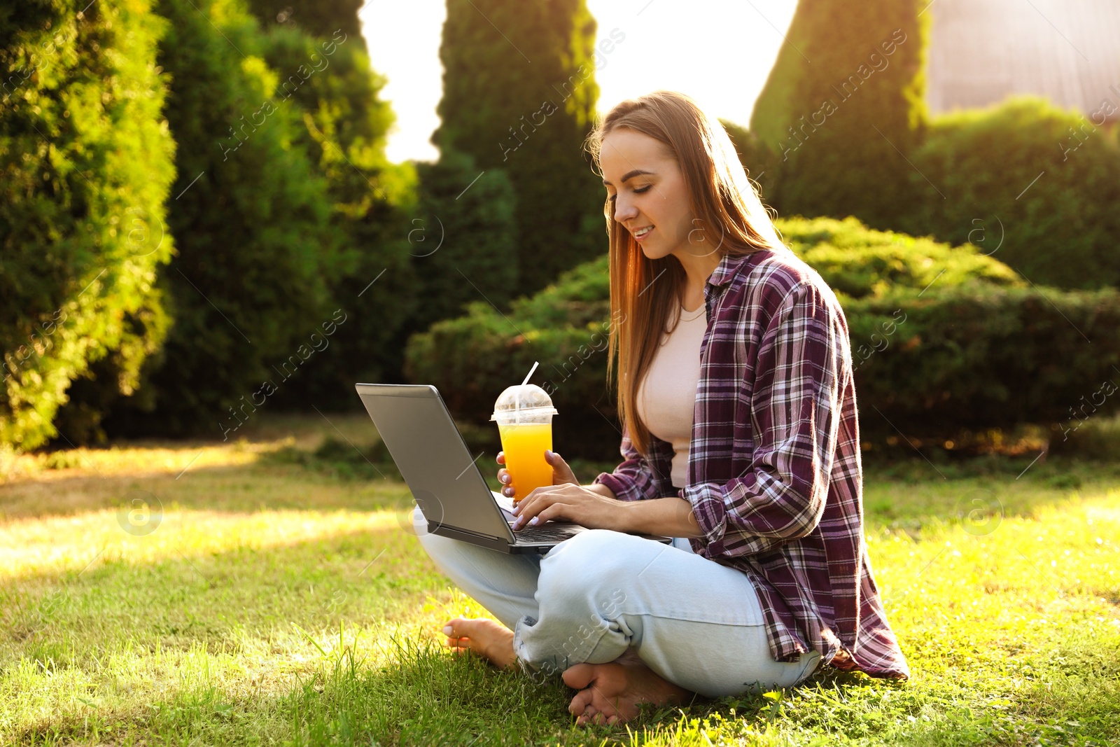 Photo of Woman using laptop on green lawn in park