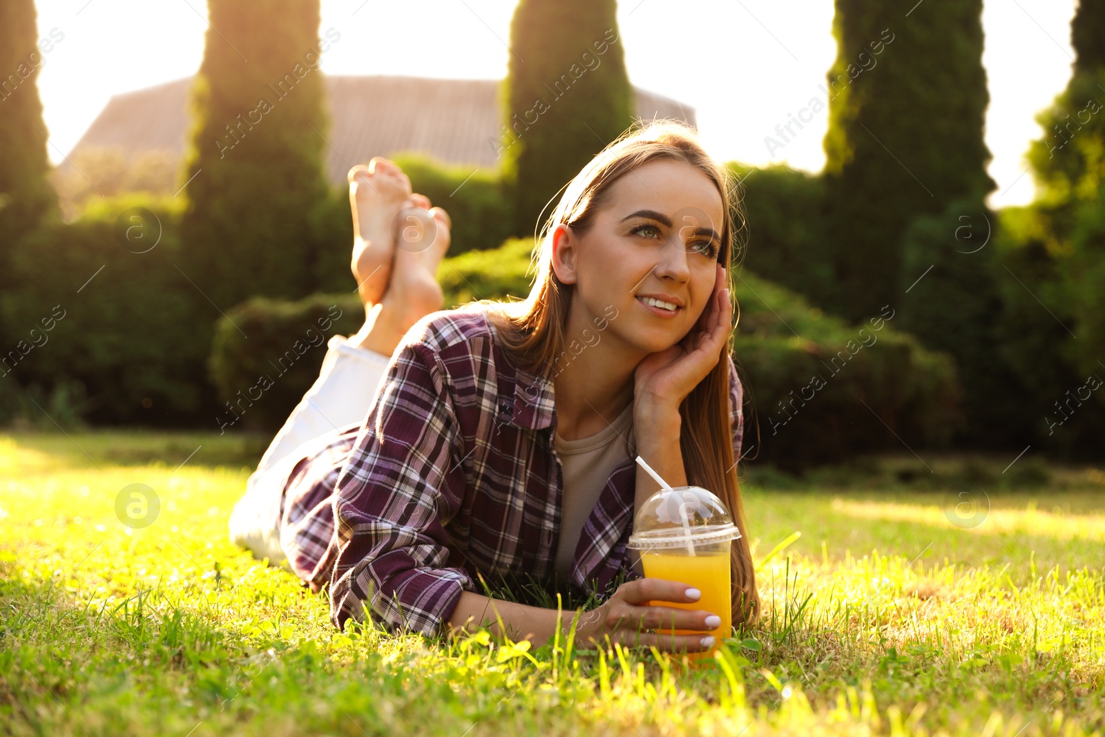 Photo of Woman with juice resting on green lawn in park