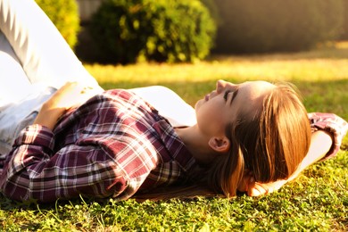 Woman resting on green lawn in park