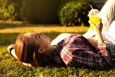 Woman resting on green lawn in park