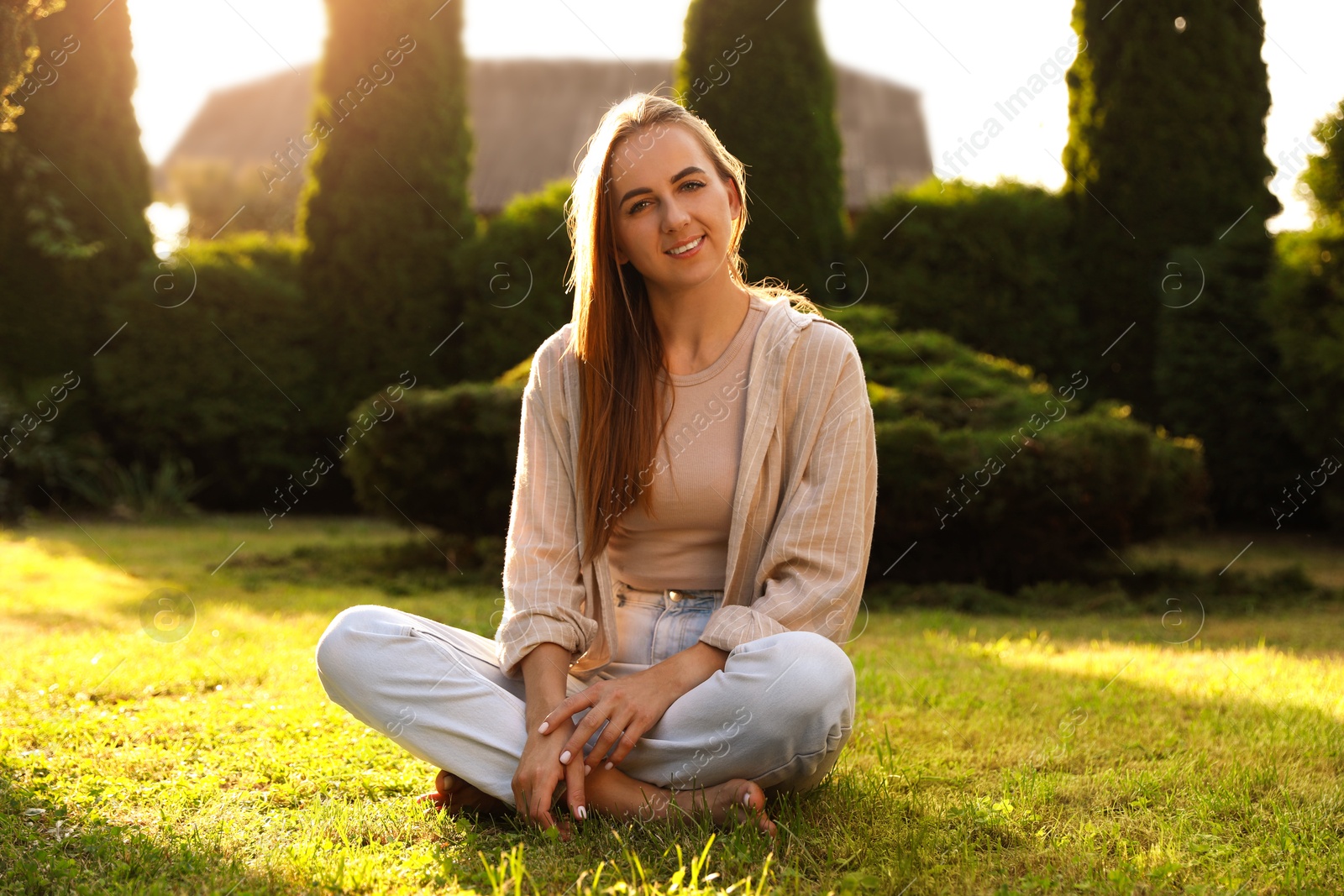 Photo of Happy woman sitting on green lawn in park