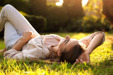 Woman resting on green lawn in park