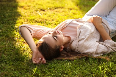 Woman resting on green lawn in park