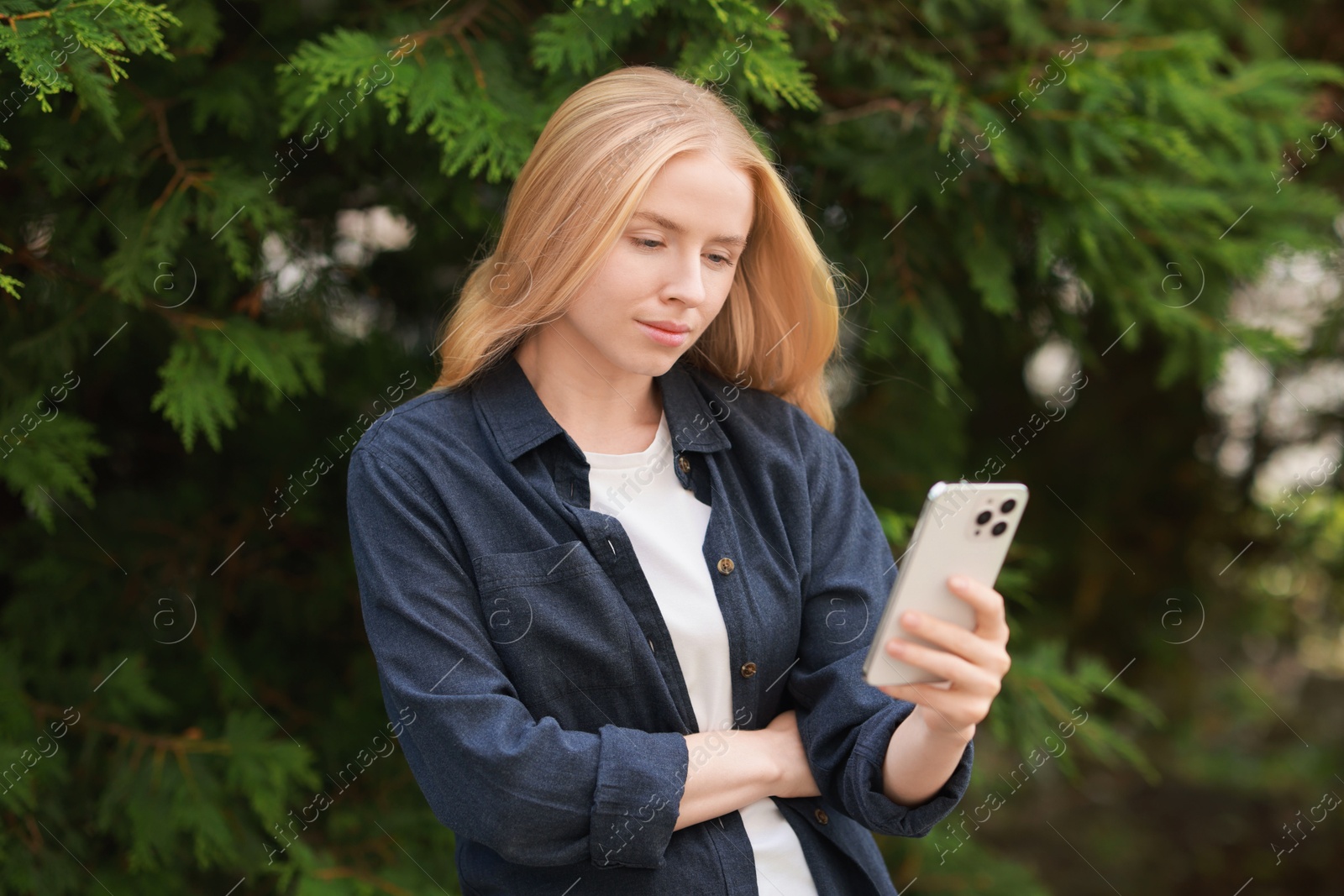 Photo of Beautiful woman using smartphone near tree outdoors