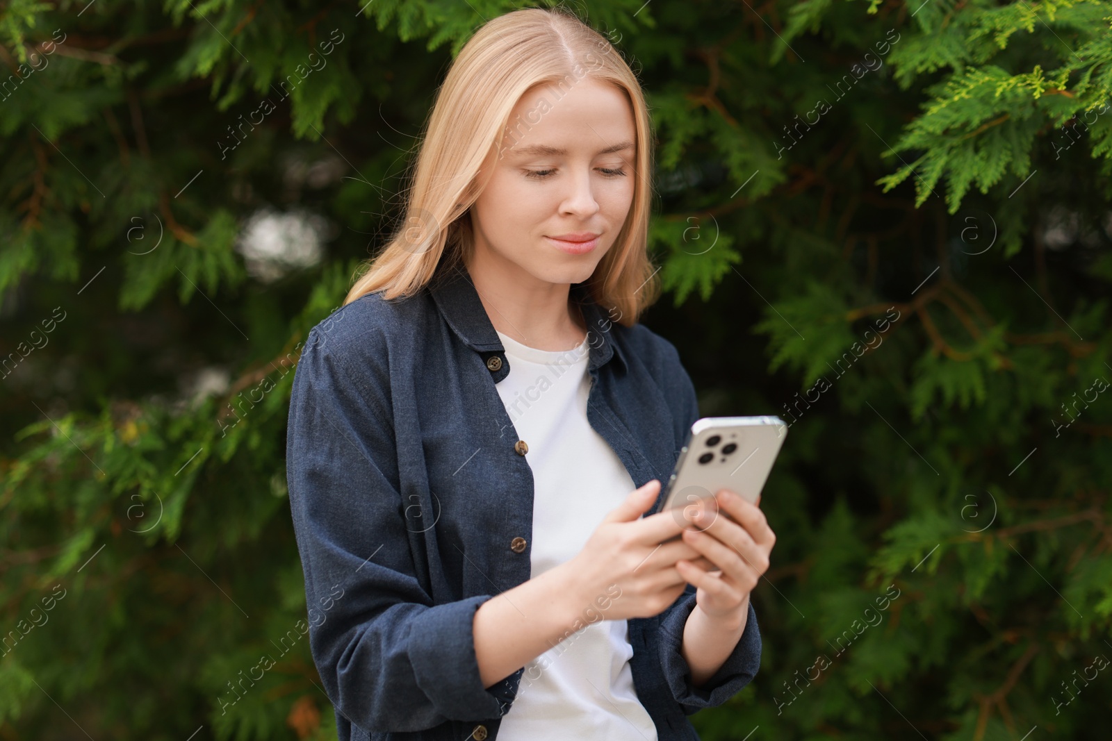 Photo of Beautiful woman using smartphone near tree outdoors