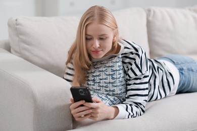 Photo of Beautiful woman using smartphone on sofa indoors