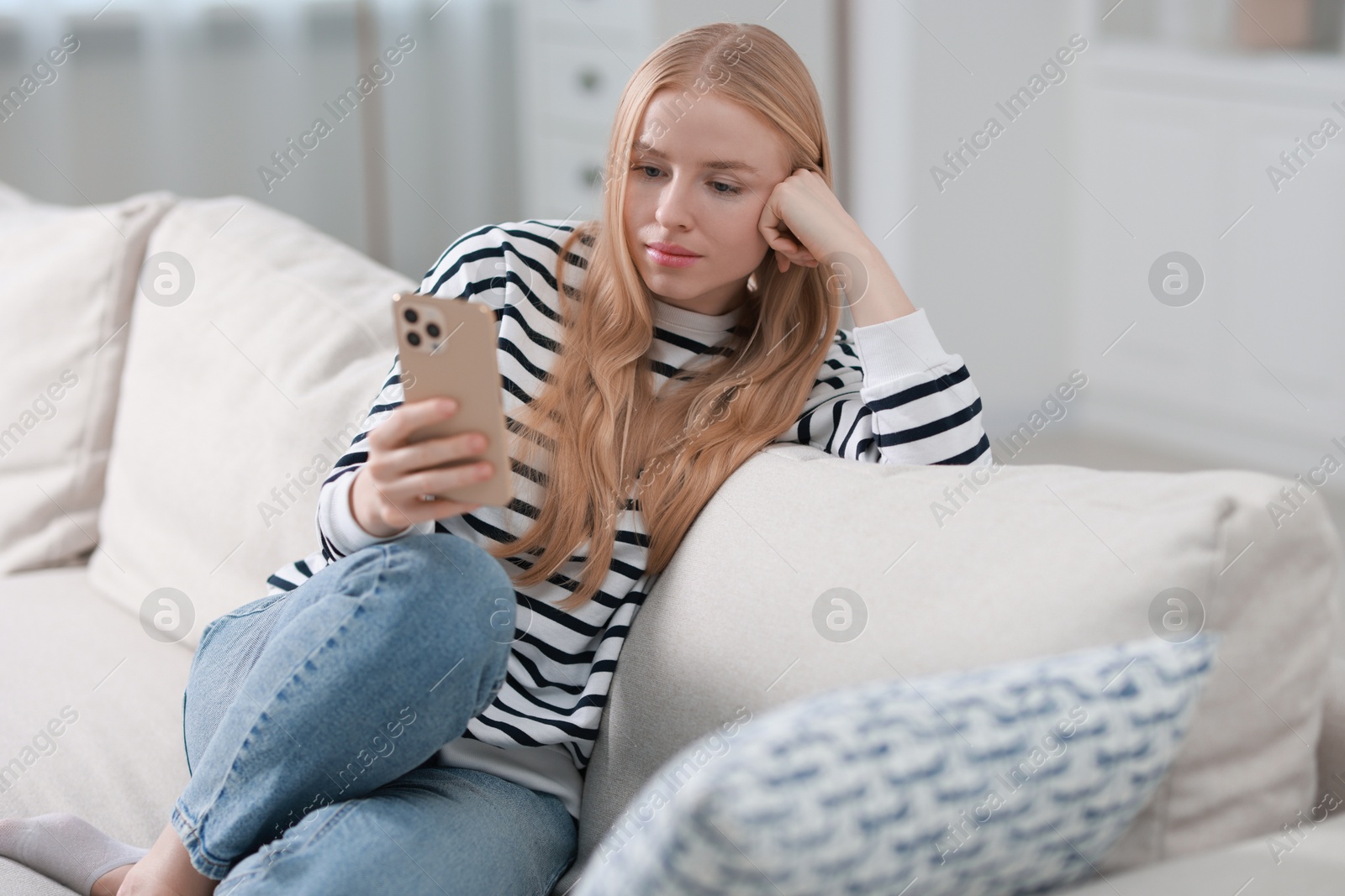 Photo of Beautiful woman using smartphone on sofa indoors