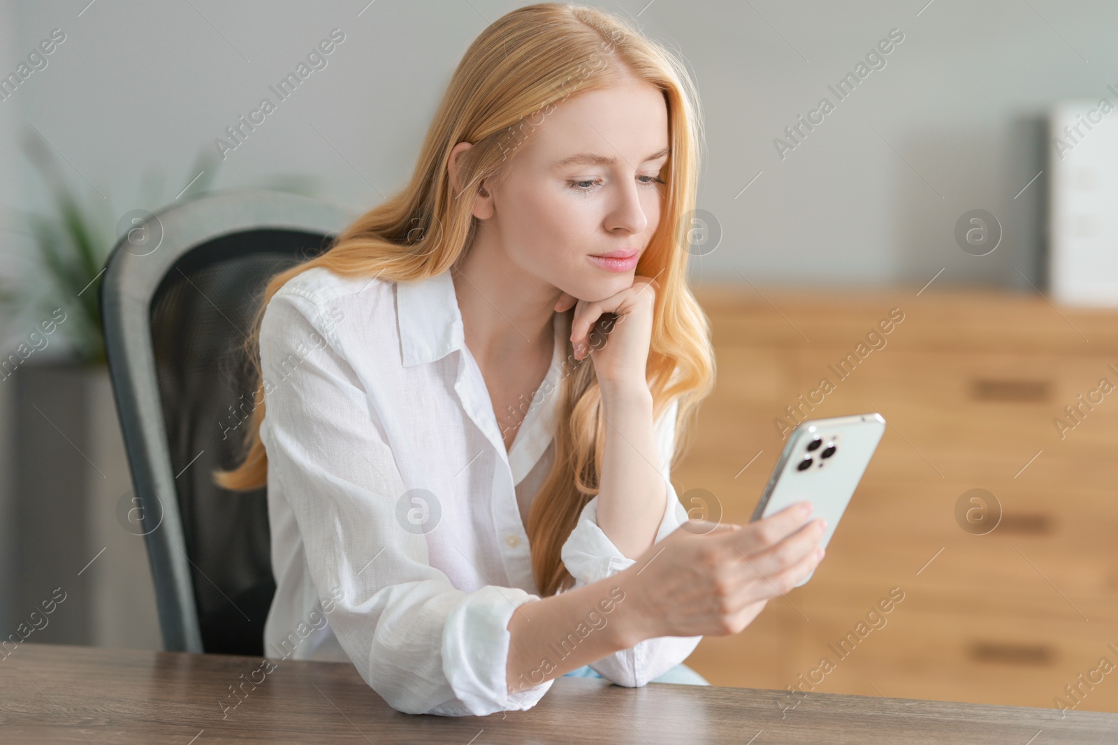 Photo of Beautiful woman using smartphone at table in office