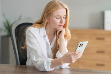 Beautiful woman using smartphone at table in office