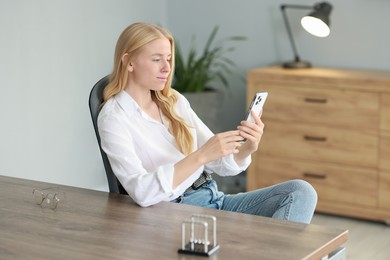 Beautiful woman using smartphone at table in office