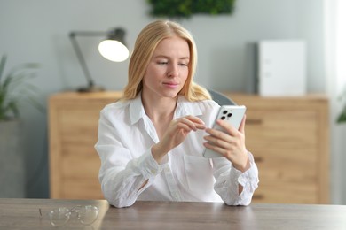 Beautiful woman using smartphone at table in office