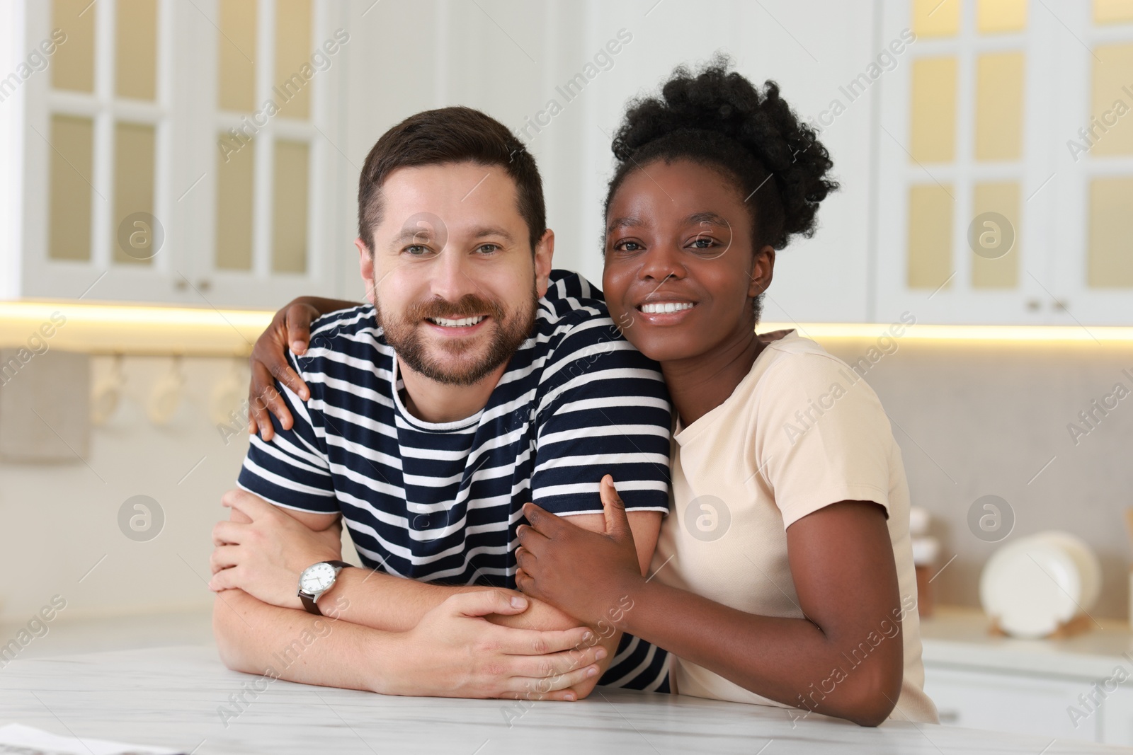 Photo of International relationships. Portrait of lovely couple at white marble table in kitchen