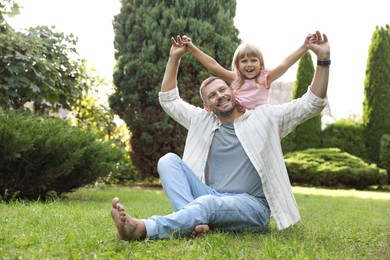 Photo of Father and his daughter spending time together on green lawn in park