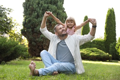 Father and his daughter spending time together on green lawn in park