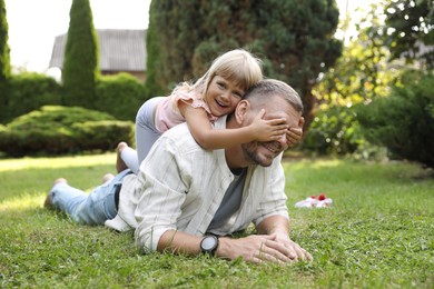 Father and his daughter spending time together on green lawn in park