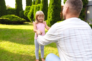 Father and his daughter spending time together on green lawn in park