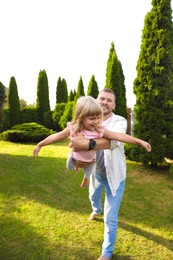 Father and his daughter spending time together on green lawn in park