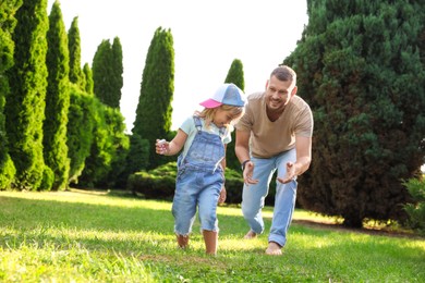 Photo of Father and his daughter spending time together on green lawn in park