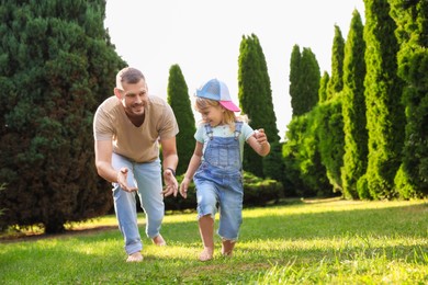 Father and his daughter spending time together on green lawn in park