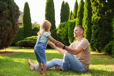 Father and his daughter spending time together on green lawn in park