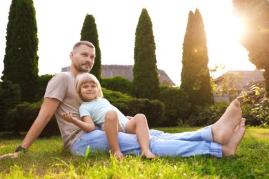 Father and his daughter spending time together on green lawn in park