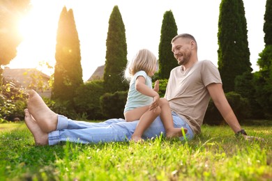 Photo of Father and his daughter spending time together on green lawn in park