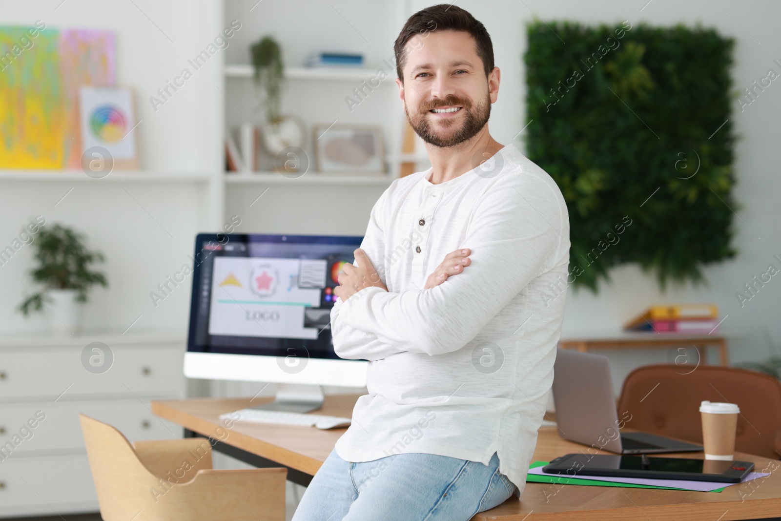 Photo of Portrait of smiling designer near table in office