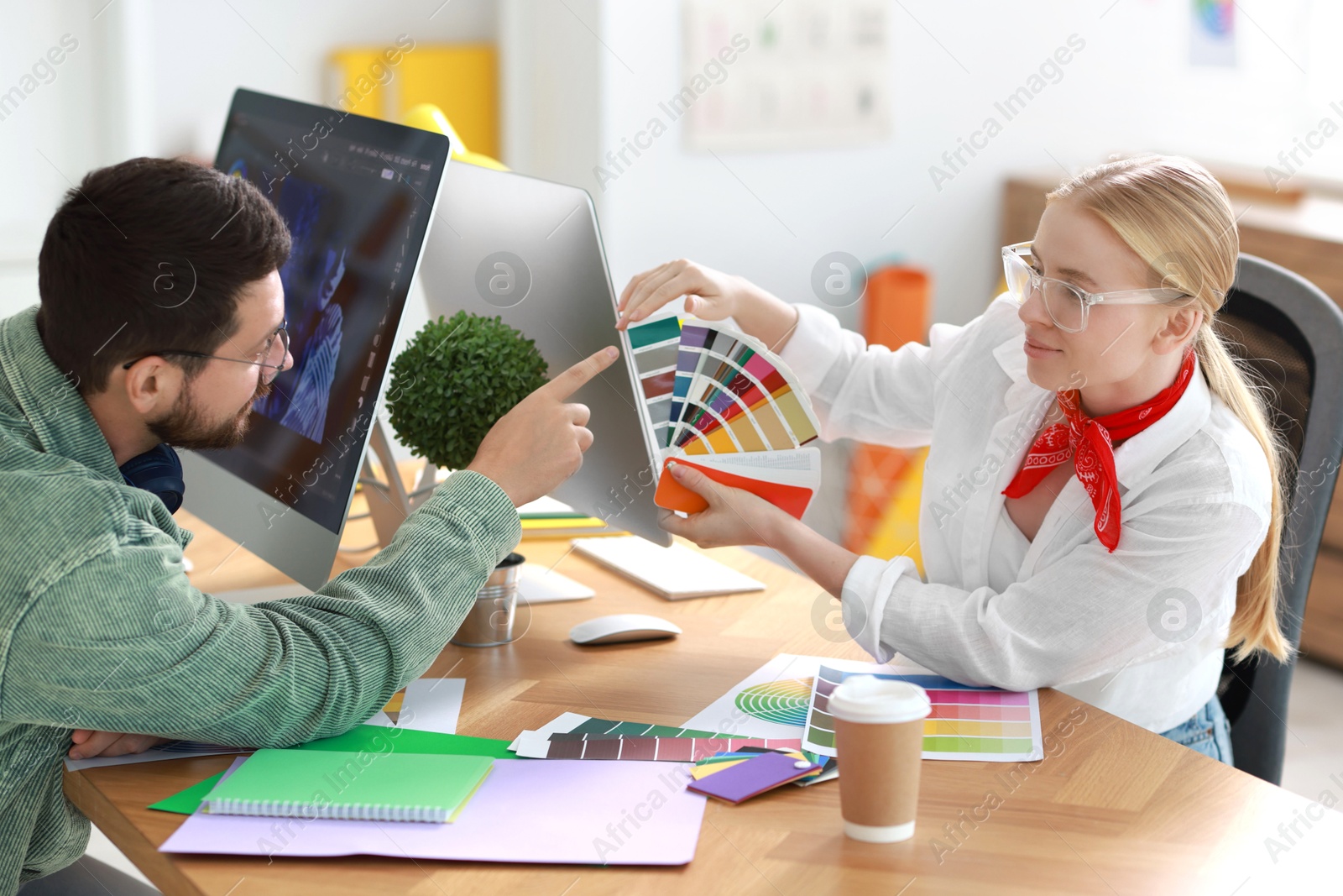 Photo of Designers with color samples working together at table in office