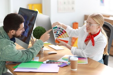 Designers with color samples working together at table in office