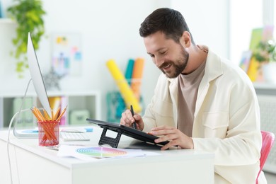 Photo of Designer working with tablet at table in office