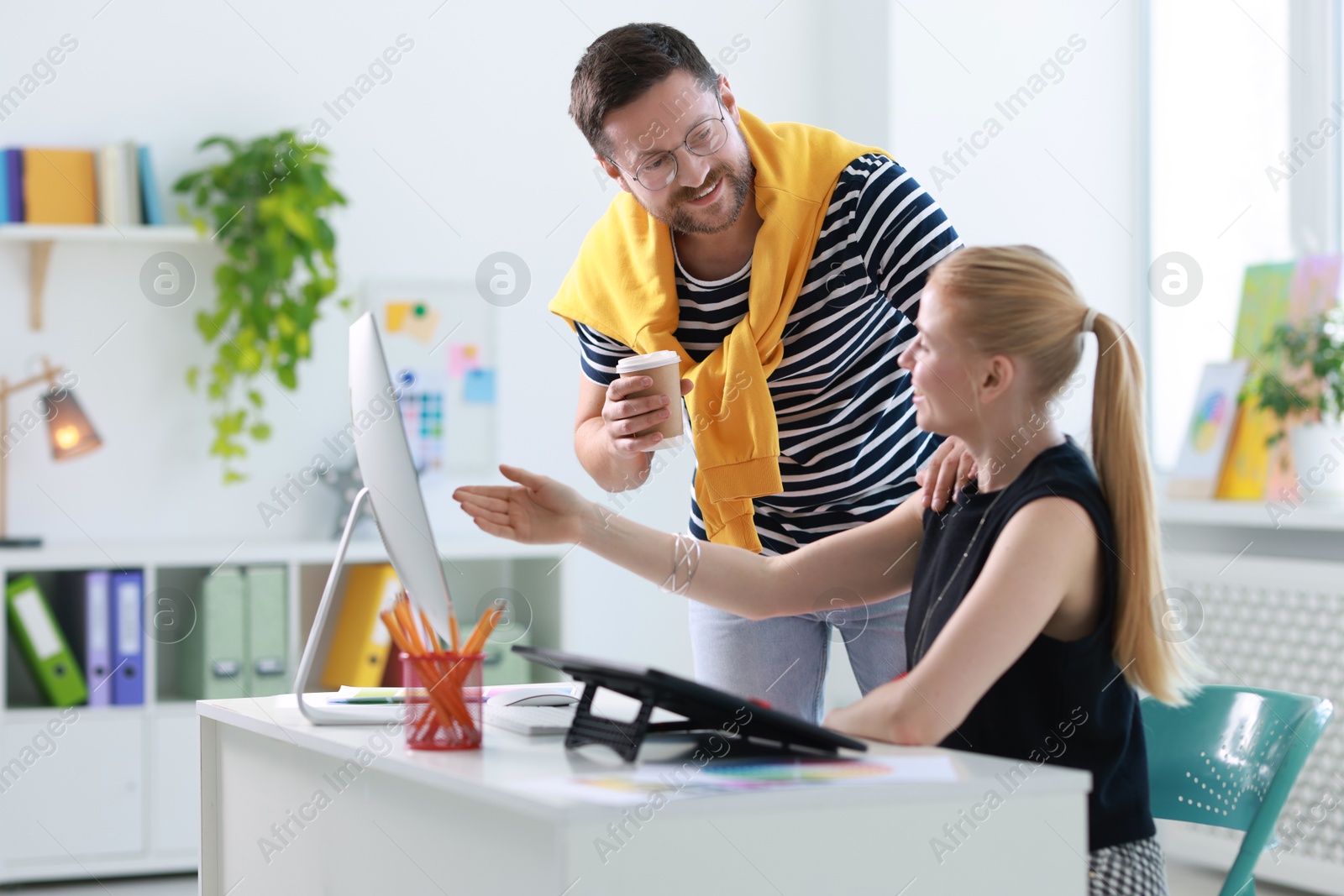 Photo of Smiling designers discussing project together in office