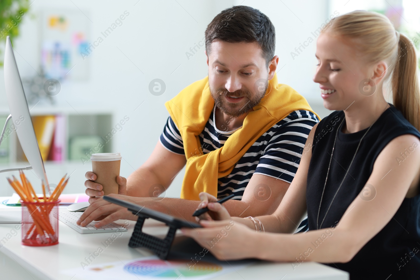 Photo of Designers with tablet working together at table in office