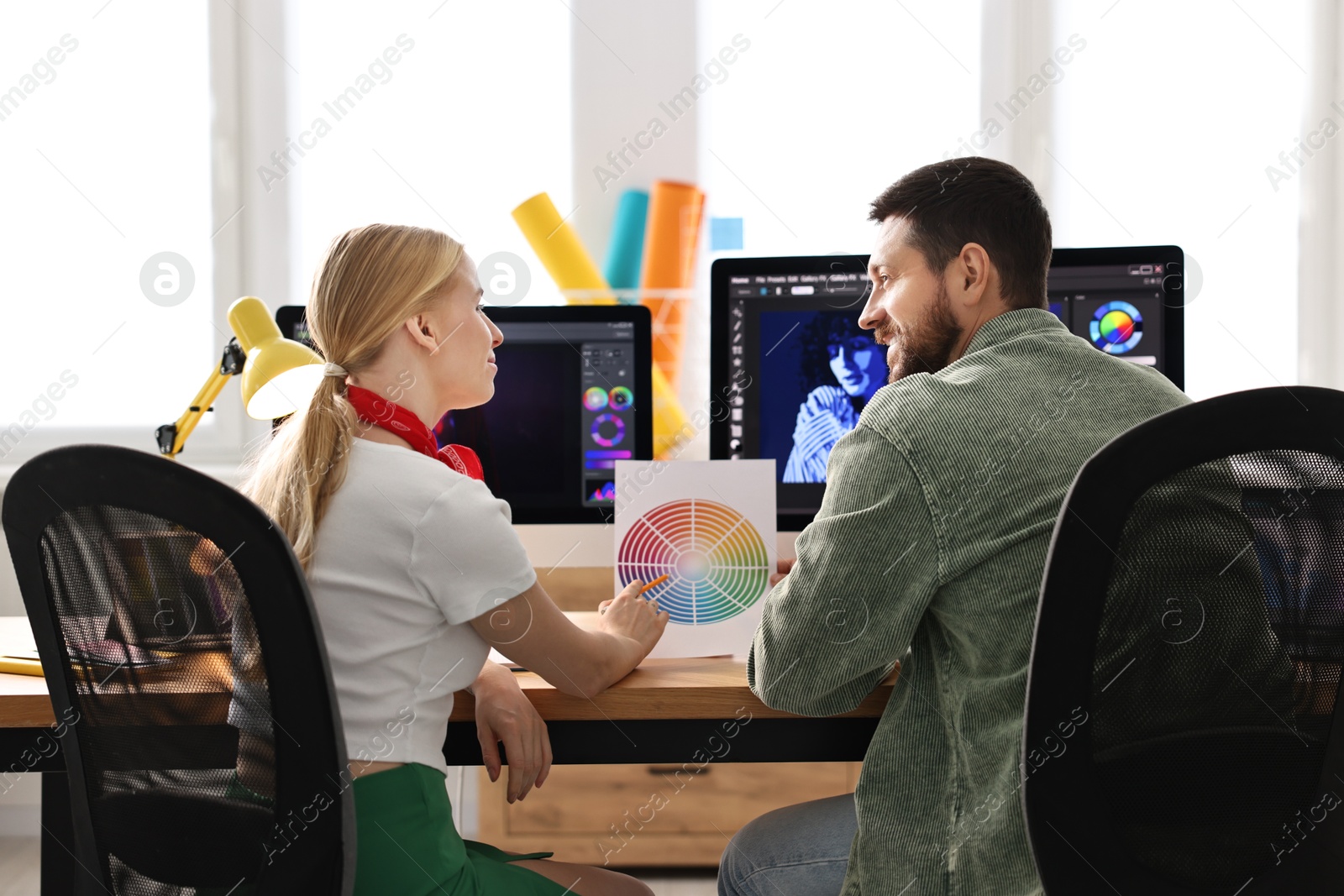 Photo of Designers with color palette working together at table in office, back view