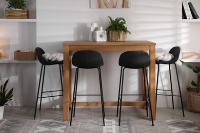 Photo of Bar stools near table in room. Interior design